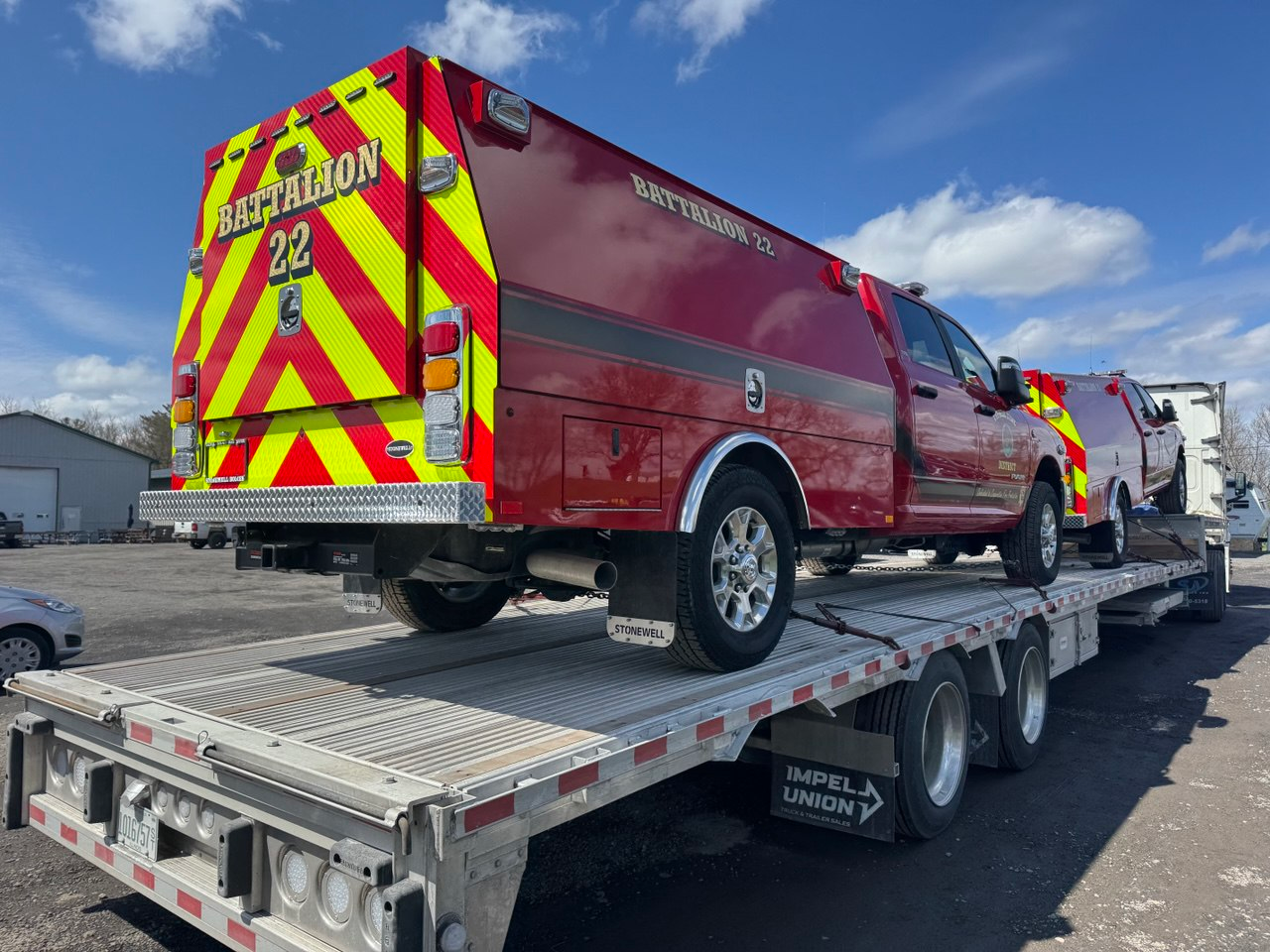 A red fire-department truck secured on a FlatbedLTL flatbed trailer