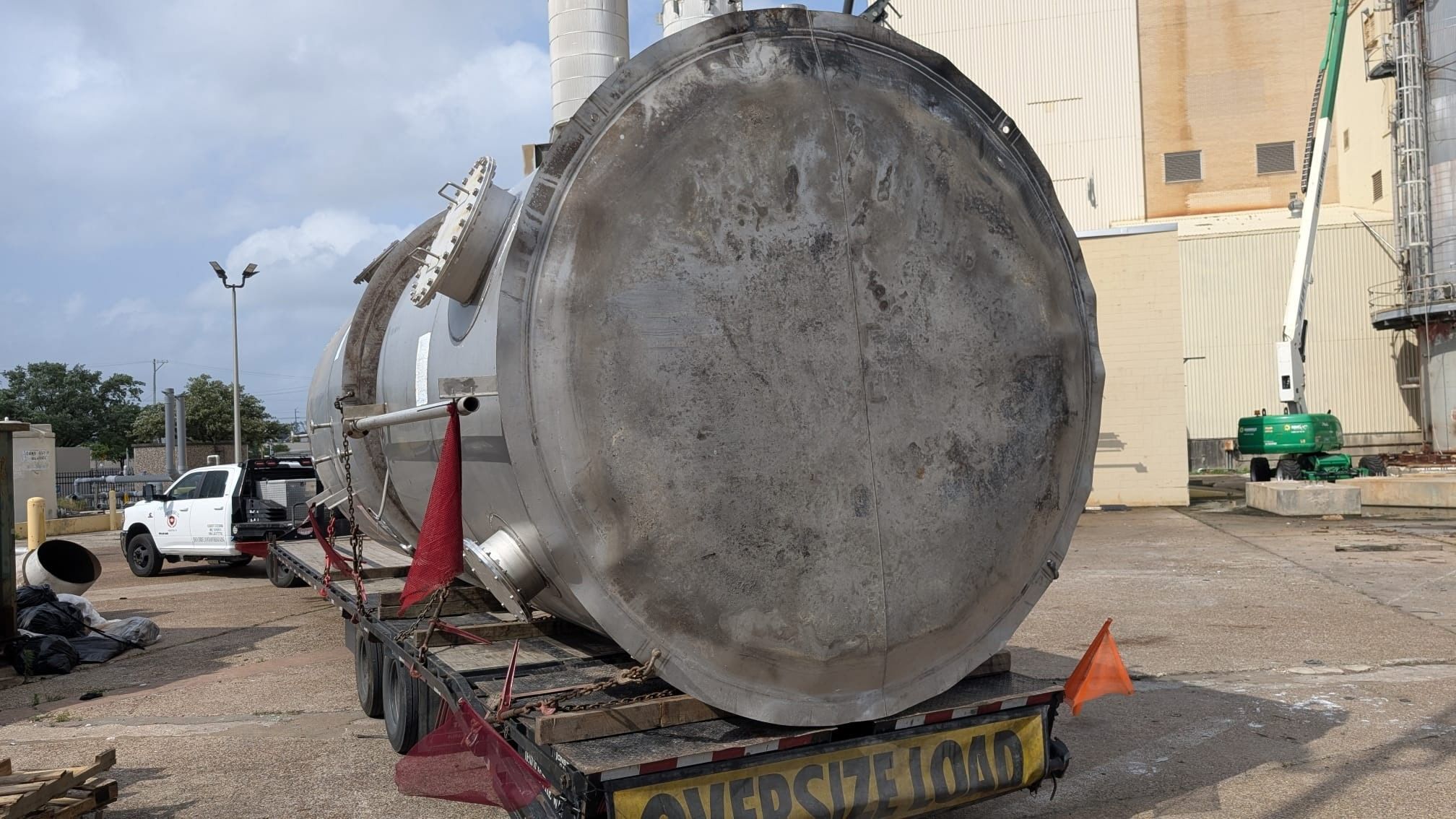 A large stainless-steel tank hauled as an oversized flatbed load